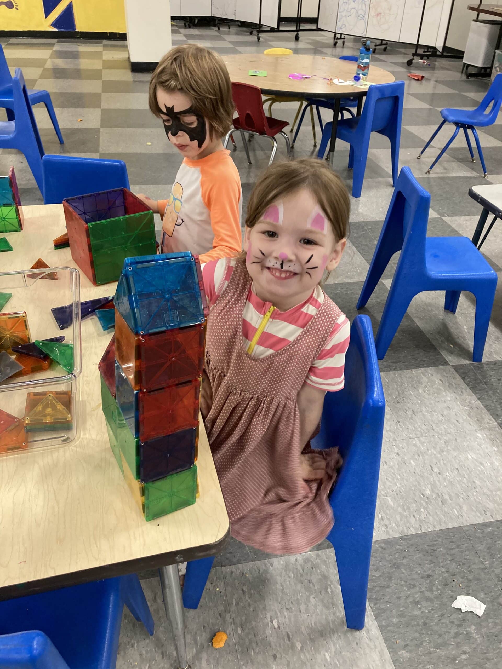 Young girl with painted face shows off her creation she built from colorful see-through squares