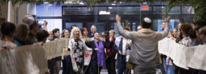 TI clergy and congregation holding up the unfurled Torah scroll on Simchat Torah