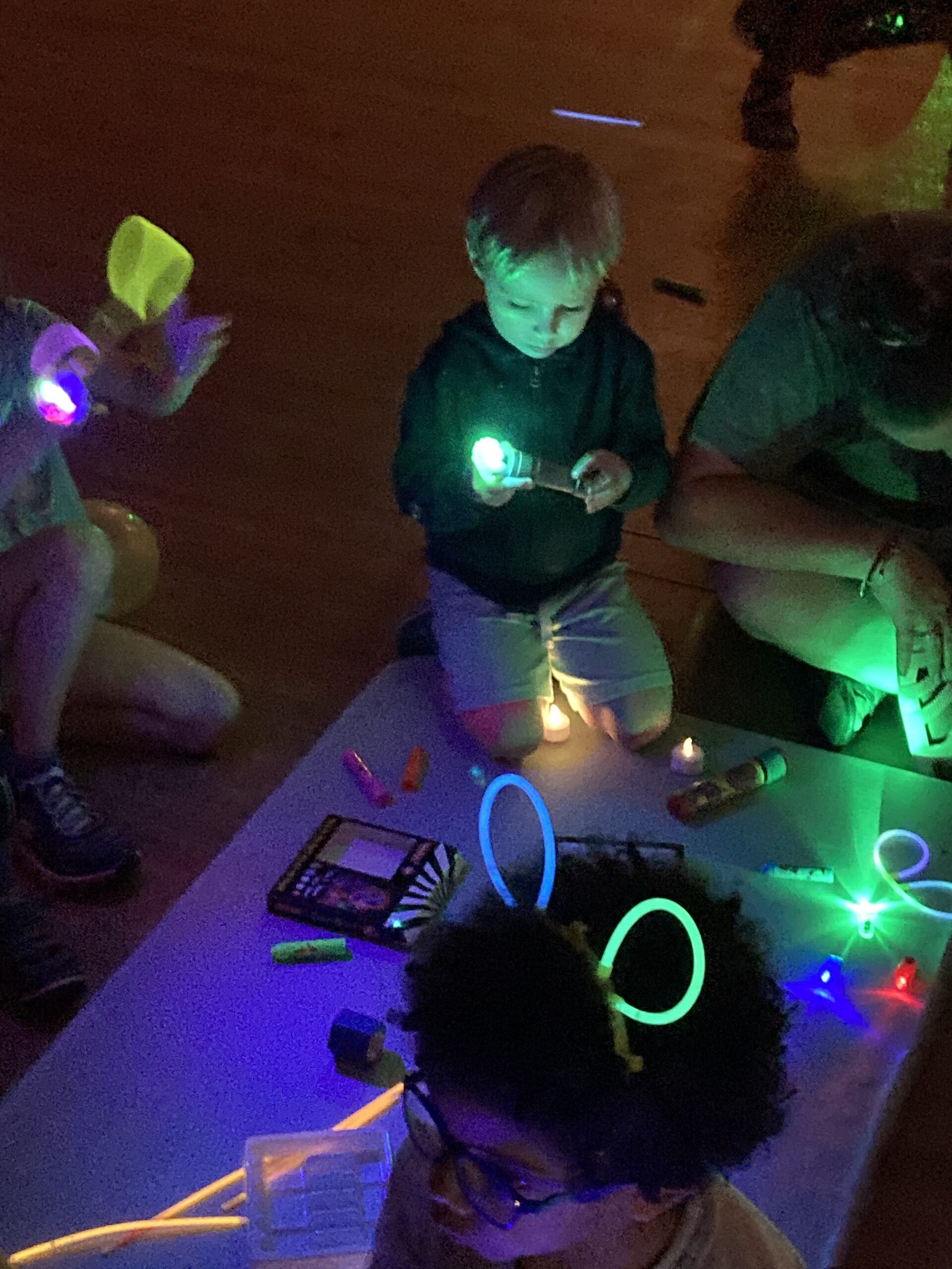 Young boy experimenting with glow in the dark objects in a dark room.