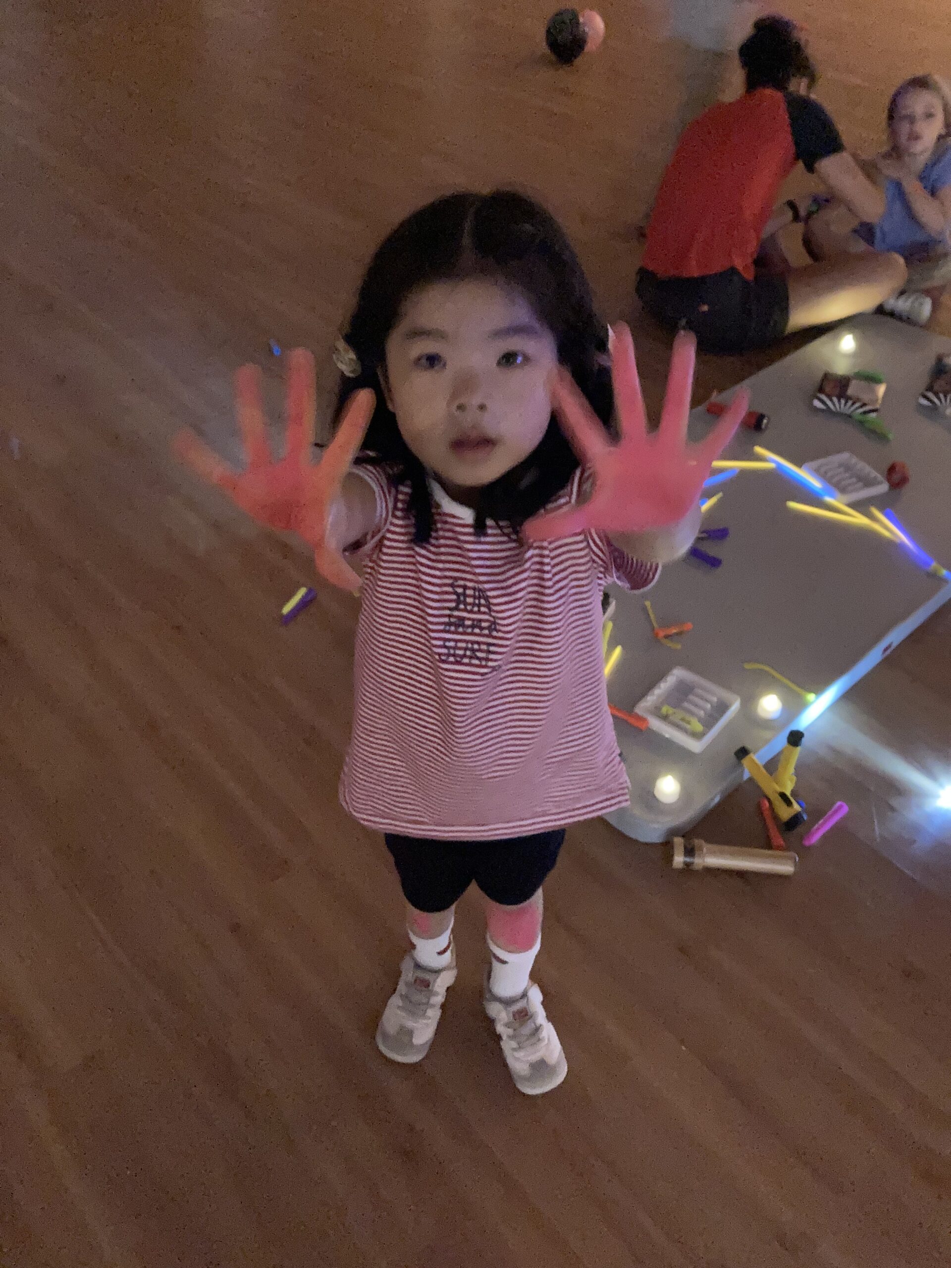 Young girl holding up her hands that are painted red